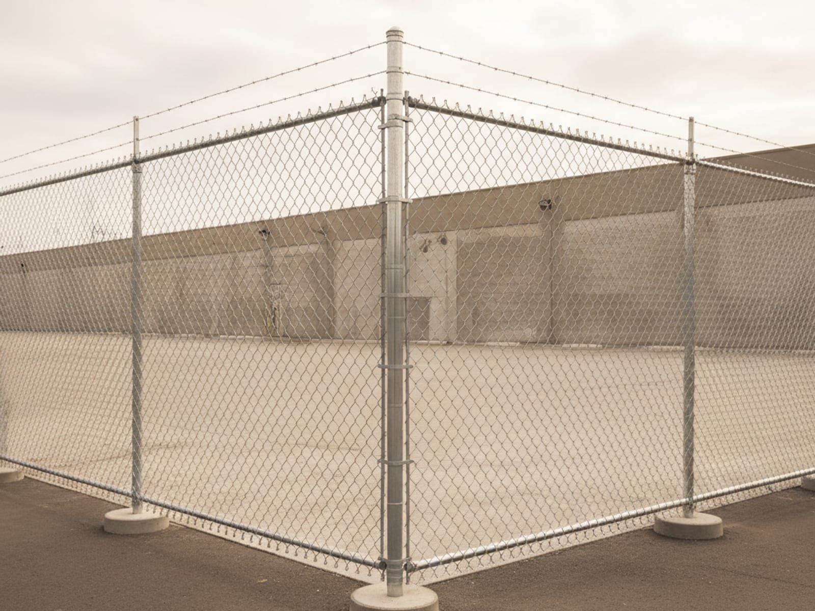 Heavy-gauge galvanized commercial chain-link fence with barbed top securing a San Diego industrial yard