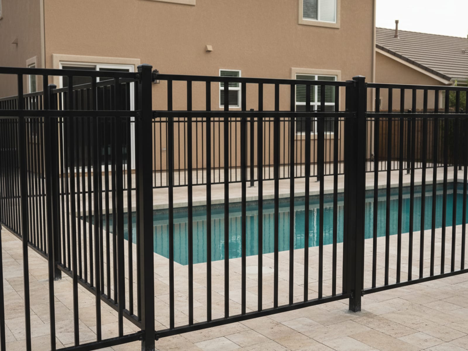 Code-compliant black ornamental aluminum pool fence with self-closing gate in a San Diego backyard